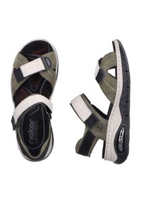 Sandales Rieker avec des sangles vert olive et blanches, fermetures Velcro ajustables, semelle intérieure rembourrée et semelle extérieure en caoutchouc noir texturé.