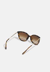Ochelari de soare cu formă de ochi de pisică, cu ramă din acetat cu model de broască țestoasă, lentile nuanțate de culoare maro și accente din metal auriu pe tempere.