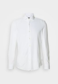 Valget pikksärk pehmest kangast, millel on terav krae, kollased nööbid ja kaardus alläär. Lõhestatud lõige mansettide detailidega.