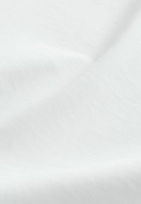 Biely bavlnený materiál s hladkou textúrou a jemným leskom, ktorý ukazuje závesný a mierne pokrčený povrchový vzor.