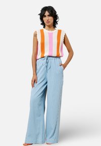 Häkeltop mit rosa, orange und weißen Streifen; hellblaue, weite gestreifte Hose mit Kordelzugbund und Seitentaschen.