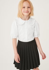 Witte korte mouwen shirt met gerimpelde kraag en knopen aan de voorkant, gecombineerd met een donkergrijs geplooid rokje met een soepele textuur en een aansluitende taille.