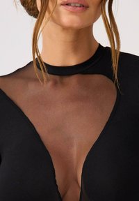 Czarny body z przezroczystą siateczką i głębokim dekoltem w kształcie litery V. Materiał jest gładki, o dopasowanym i bezszwowym wyglądzie.