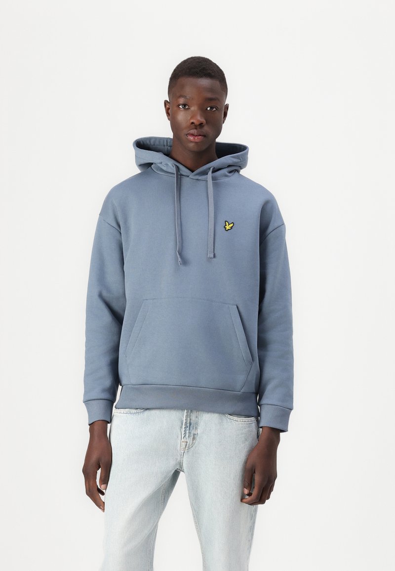 Hoodie u svijetloplavom pamuku, s kenguruvim džepom i malim žutim logom. Jednostavna tekstura s rebrastim manžetama i rubom.