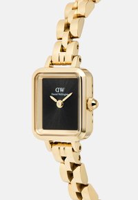 Gold rectangular watch with a black face, featuring gold hands and hour markers. The band has a linked design, enhancing its metallic texture.