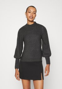 Dark gray ribbed sweater with a high neckline and long, puffed sleeves, paired with a black mini skirt featuring a side slit.
