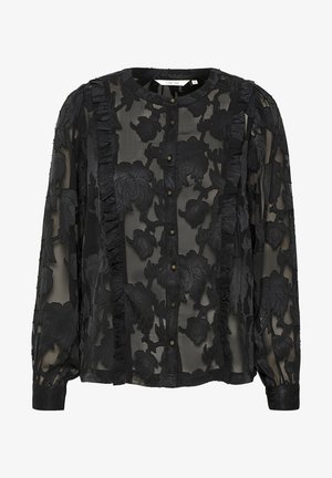 Blusa nera trasparente con ricami floreali, accenti di volant strutturati, scollo rotondo e chiusura frontale con bottoni. Maniche lunghe con polsini aderenti.