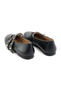 Zapatos de cuero negro con punta redondeada, tacón bajo y acentos decorativos de correa con múltiples agujeros. Textura suave con un diseño minimalista.