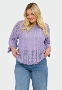 Lichtpaarse gehaakte gebreide trui met een losse pasvorm en 3/4 bell mouwen, gedragen over high-waisted blauwe jeans met een tekstuurdesign.