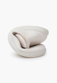 Chaussure flexible beige clair pliée à plat, montrant une tige en tissu doux et une semelle en caoutchouc texturée conçue pour un emballage facile ou les voyages.