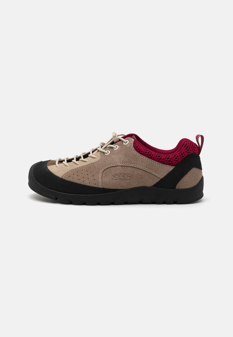 Chaussure avec une tige en daim beige, une semelle en caoutchouc noir, des accents en mesh rose et des lacets gris. Présente des perforations pour la respirabilité et une languette.