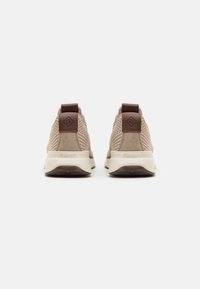 Beige athletic shoes with a mesh upper, suede accents, and brown heel tab. Thick white midsole and textured brown outsole.