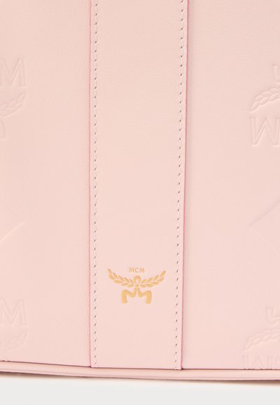 Τσάντα από ροζ δέρμα με ανάγλυφο λογότυπο και χρυσές λεπτομέρειες. Διαθέτει απαλό υφή και αντίθετη ραφή. Μινιμαλιστικός σχεδιασμός με διακριτική σήμανση.