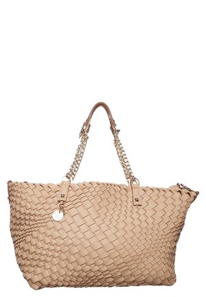 Sac fourre-tout en cuir tissé beige avec poignées en chaîne dorée et un pendentif métallique rond suspendu près du haut.