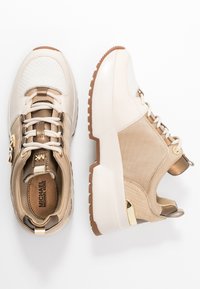 Baskets beige à finition texturée, avec un bout blanc perforé, des accents dorés et une semelle intermédiaire blanche épaisse. Design lacé avec col rembourré.