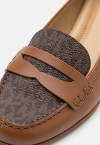 Mocassins en cuir marron avec un panneau en tissu marron foncé texturé à motif et un accent décoratif en découpe sur la bride. Fini lisse.