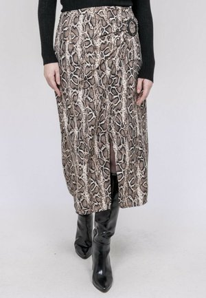 Femme portant une jupe midi imprimé serpent avec une fente avant et une ceinture noire, associée à des bottes noires montantes jusqu'aux genoux et un pull noir.