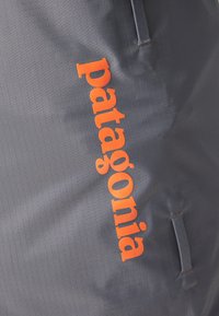 Gray fabric bag with textured surface and orange "patagonia" logo. Features include stitching and a side handle.