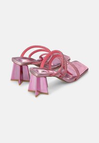 Roze metallic hakken sandalen hebben een vierkante neus, meerdere dunne banden en geometrische hakken met een doorschijnende uitstraling en een gouden basis.