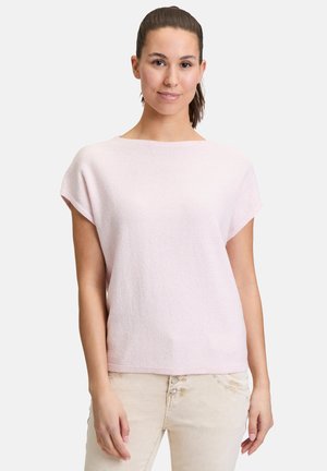 Haut rose clair à manches courtes en tissu texturé, avec un large col et une coupe décontractée. Porté avec un pantalon de couleur claire.