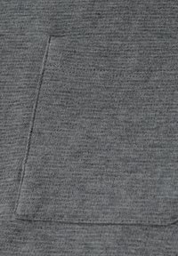 Tessuto grigio con un motivo texturizzato e una piccola tasca applicata sul davanti. Il materiale sembra morbido ed è tessuto in modo uniforme.