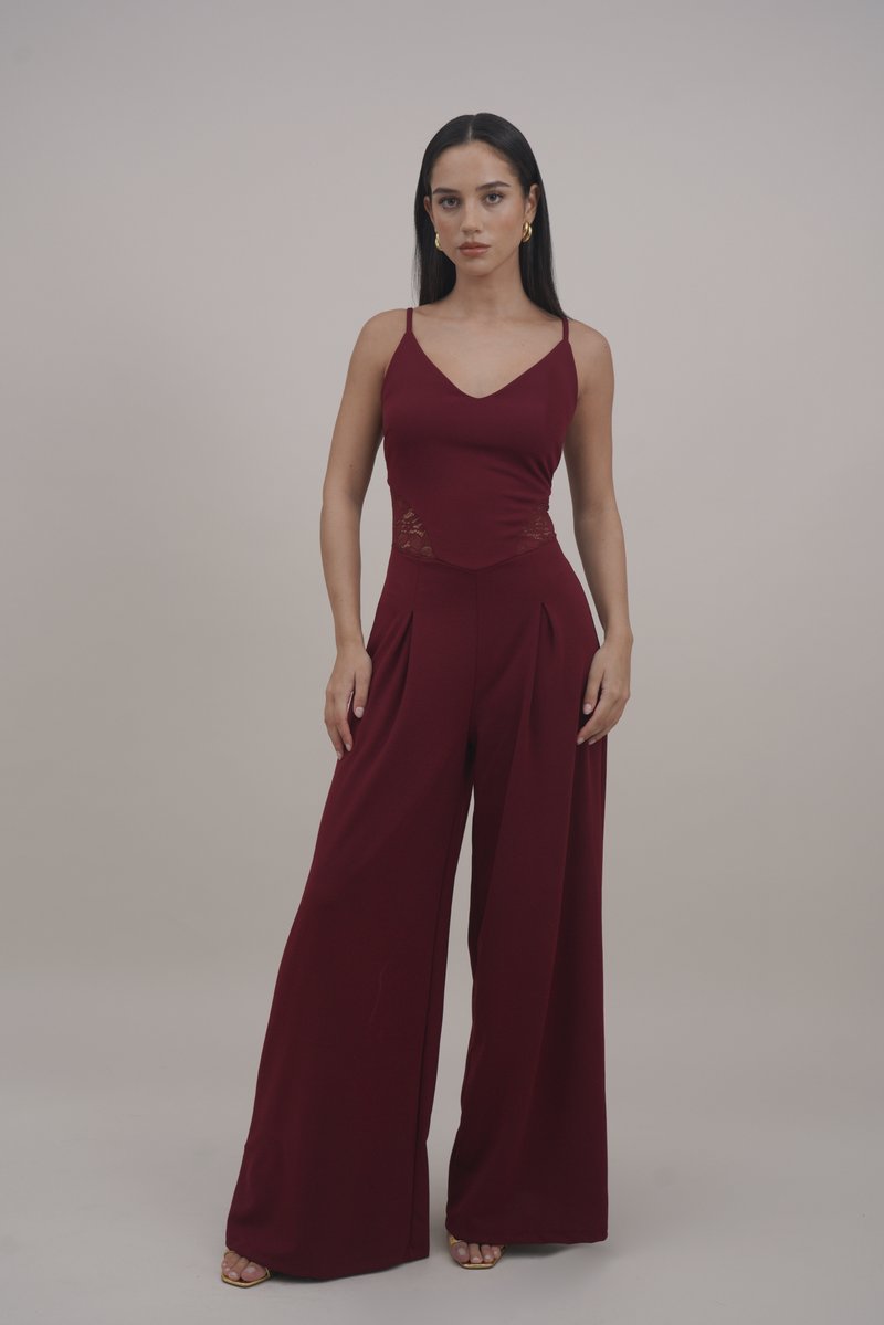 Combinaison bordeaux avec un corsage ajusté, des accents en dentelle, un pantalon large et des fines bretelles, fabriquée dans un tissu lisse et léger.