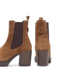 Hnedé semišové členkové topánky s elastickými bočnými panelmi, blokovým podpätkom a textúrovanou podrážkou. Na zadnej strane majú pútko pre jednoduchšie obúvanie.