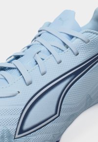 Svetlo modra športna čevlja s teksturirano tkanino, svetlo modrimi vezalkami in temno modrim logotipom Puma na strani.