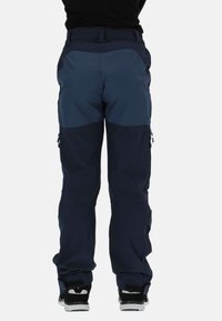 Granatowe spodnie z ciemnogranatowymi akcentami, wyposażone w kieszenie na zamki oraz zwężane nogawki. Wykonane z trwałej tkaniny odpowiedniej do użytku na zewnątrz.
