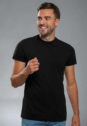 Black short-sleeve t-shirt with a crew neckline, made of smooth fabric. Model is smiling, wearing it with light blue jeans.
