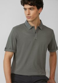 Polohemd in olivgrün, mit einem knopfbaren Kragen, kurzen Ärmeln mit hochgekrempelten Bündchen und einem glatten, strukturierten Stoff.