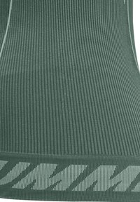 Gros plan sur un tissu côtelé vert avec un motif à rayures diagonales près du bord inférieur.