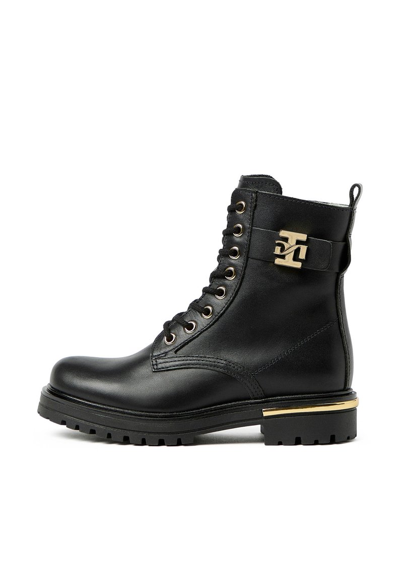 Bottine en cuir noir avec ferrures dorées, bout rond, design à lacets et semelle en caoutchouc texturée. Dispose d'une bride décorative.