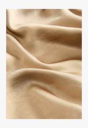 Satin fabric in a warm, light beige color, featuring a smooth, glossy texture with subtle folds and curves throughout.