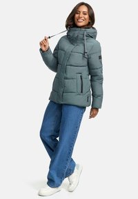 Gray puffer jacket with a high collar, side zippers, and adjustable drawstrings. Worn over light blue wide-leg jeans and white sneakers.