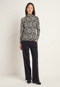 Long-sleeve top with a black and cream geometric pattern, paired with black wide-leg trousers and black heeled ankle boots.