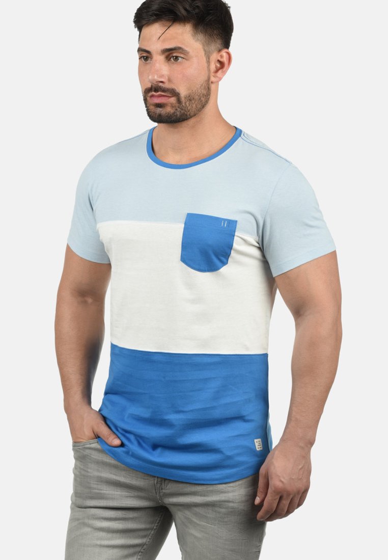 Blå og hvit fargeblokkert t-skjorte med rund hals, kort erme og en liten brystlomme. Laget av mykt stoff.