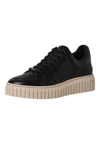 Baskets en cuir noir avec un bout arrondi et une semelle en caoutchouc beige texturée et épaisse. Elles sont dotées de lacets plats et d'un logo discret sur le côté.
