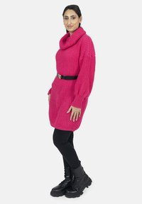 Stickad rosa klänning med cowl-neck, ribbstruktur, långa ärmar och svart bälte. Kombinerad med svarta leggings och kängor.