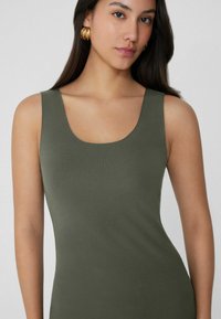 Olivově zelený žebrovaný top s kulatým výstřihem a širokými ramínky, vyrobený z měkké, elastické látky. Hladký povrch, přiléhavý střih.