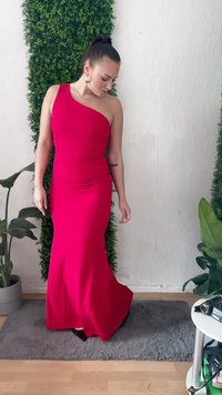 Vestido rojo ajustado de un solo hombro con tejido recogido, silueta larga hasta el suelo, textura suave y un brillo sutil. Acentuado por un zapato negro.
