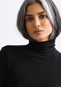 Black turtleneck top with a slim fit, made from a smooth fabric. Features a high collar and long sleeves with a minimalist design.