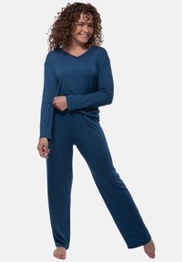 Tummansininen kotivaatteiden setti, joka sisältää pitkähihaisen, V-pääntiellä varustetun paidan ja suorat housut, valmistettu pehmeästä ja joustavasta kankaasta. Sileä rakenne, mukava istuvuus.