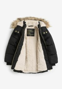Schwarze Daunenjacke mit einer Kapuze aus Kunstfell, cremefarbiger Schafwolle-Fütterung, goldenen Beschlägen und Reißverschluss. Innenetikett sichtbar.