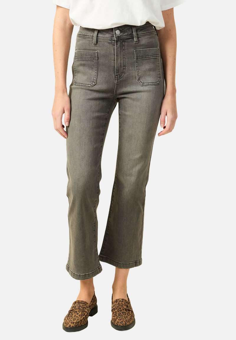 Jeans z wysokim stanem, szare dżinsy z bocznymi kieszeniami, ściągające się w dół nogawki oraz subtelnymi detalami przeszyć, zestawione z klapkami w panterkę.