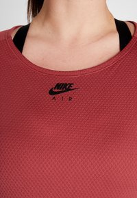 Rode gestructureerde sportshirt met ronde hals, met een zwart Nike Air-logo op de borst. De stof heeft een diamantpatroon en een slim fit ontwerp.