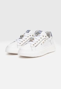 Baskets en cuir blanc avec une semelle épaisse, ornées de gemmes décoratives sur les lacets et d'œillets en métal, avec un accent bleu clair sur la languette.