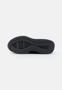 Suela de zapatilla de goma negra con un agarre texturizado y con patrón. Presenta un logo ligeramente elevado y una forma contorneada para mayor soporte.