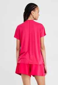 Roze T-shirt met korte mouwen, gemaakt van gladde stof, met een ontspannen pasvorm en ronde halslijn, gecombineerd met bijpassende shorts.
