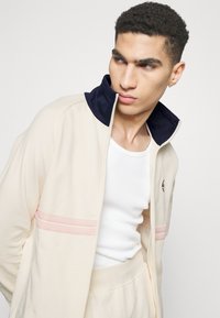 Sergio Tacchini DALLAS TRACK - Jaka ar rāvējslēdzēju - gardenia/maritime blue